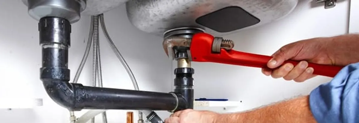 Garbage disposal repair technician tightening the sink drain and disposal connection in Bakersfield, CA