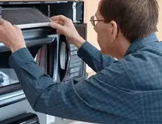 Appliance repair technician replacing a microwave vent filter in Bakersfield, CA