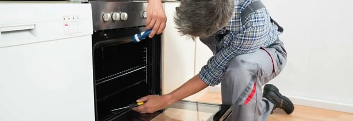 Oven repair technician inspecting and servicing an electric oven in Bakersfield, CA