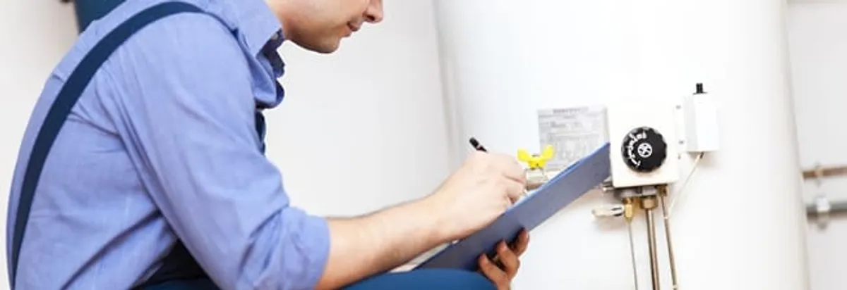 Water heater repair technician inspecting the unit and recording service notes in Bakersfield, CA
